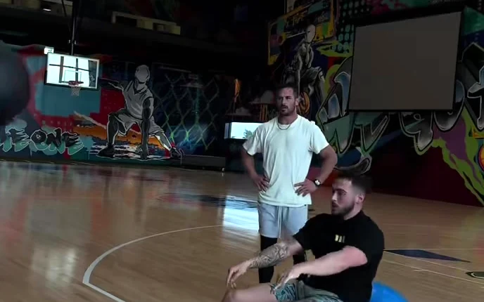 Eric coaching Danny Amendola through a stability-ball drill on a basketball court
